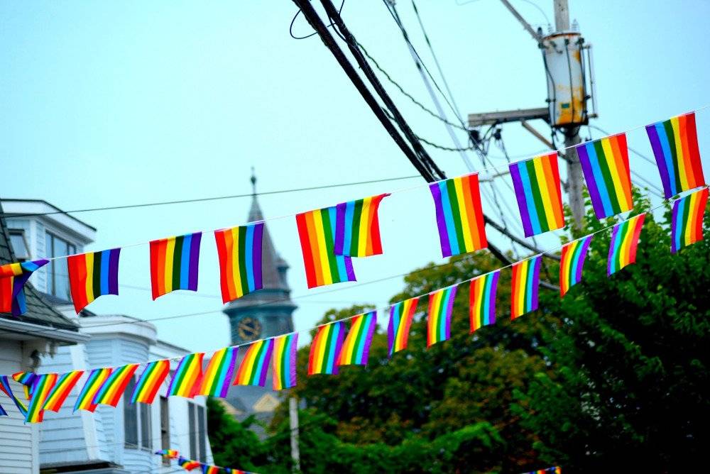 Rainbow flags displayed along buildings on Commercial Street in Provincetown, symbolizing the town's vibrant and inclusive LGBT community
